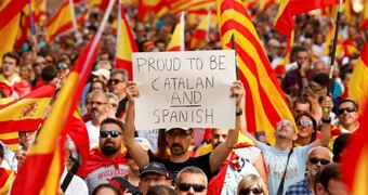 A man holds a sign saying "proud to be Catalan and Spanish", in a Catalonia protest.