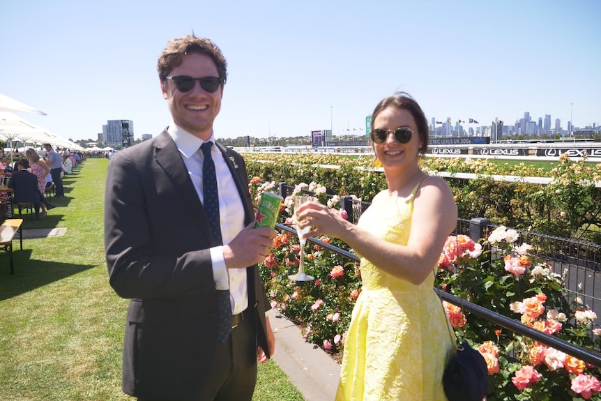 A man and woman cheers each other with drinks trackside at the Melbourne Cup. 