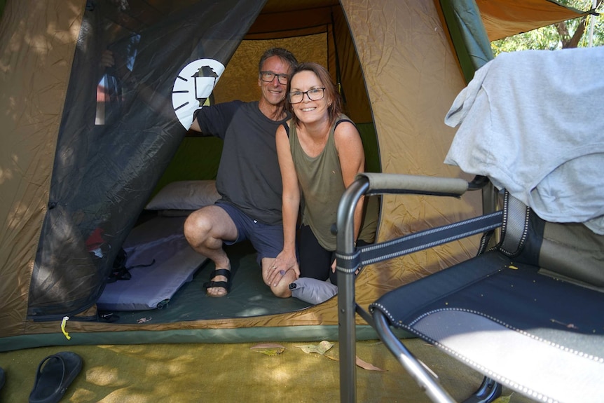 John Callanan and Jane Denny are inside a tent smiling at the camera. They are in a camp site.