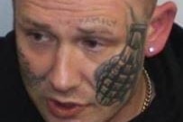 A man with short hair and a tattoo of a grenade on his face.
