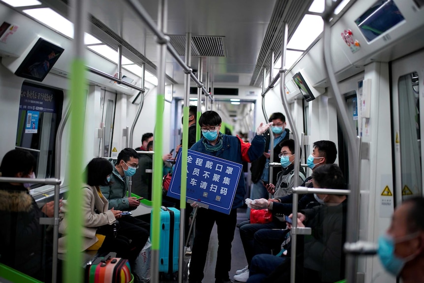 The interior of a train carriage in Wuhan, China with about 10 passengers who are all wearing face masks.
