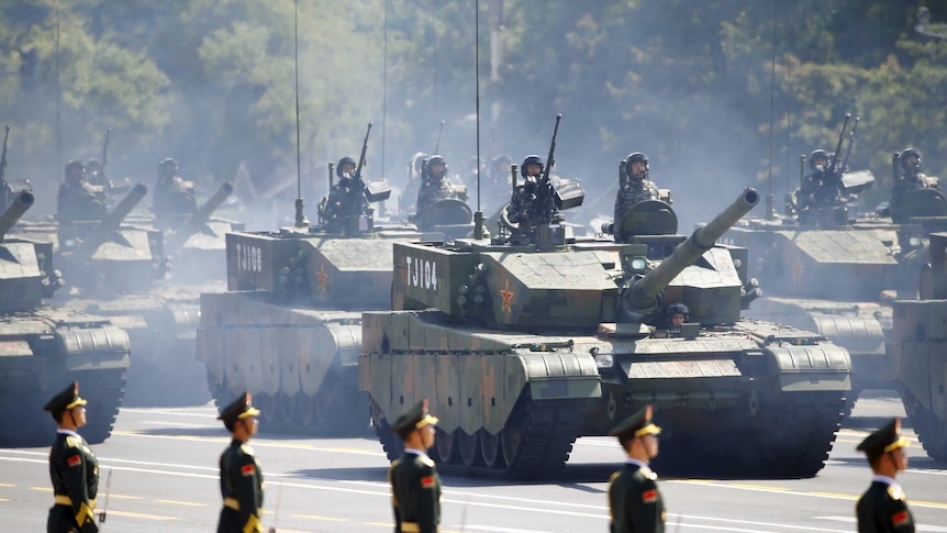 Chinese soldiers stand in armoured vehicles during a military parade