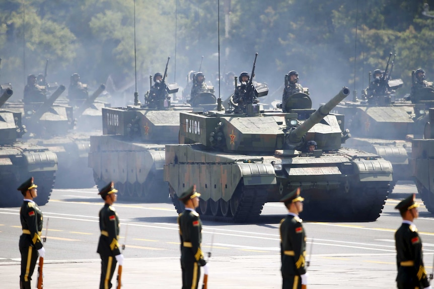 Chinese soldiers stand in armoured vehicles during a military parade