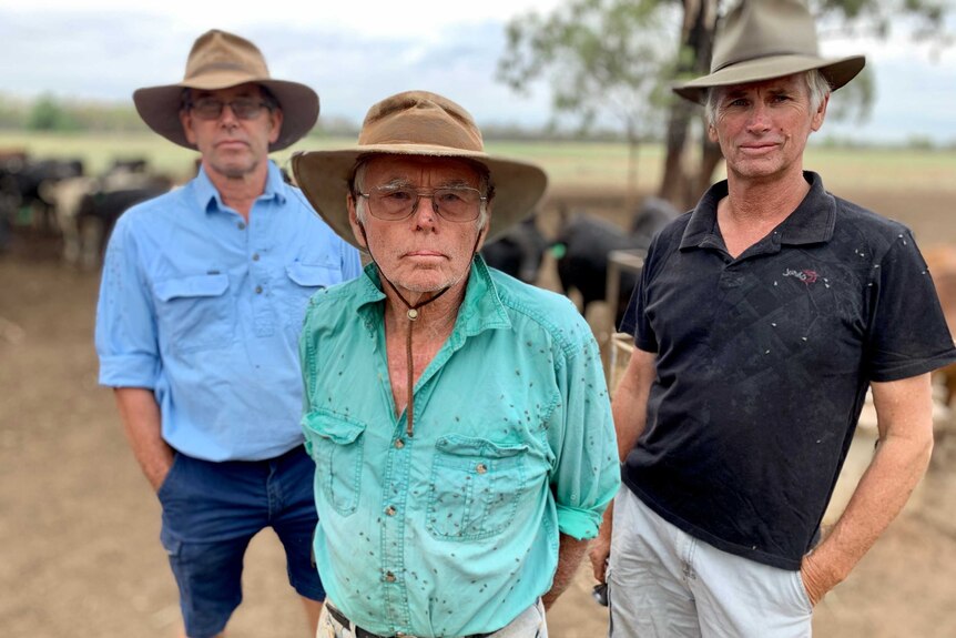 Three men wearing hats on a farm.