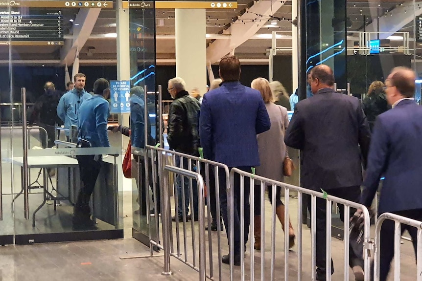 A line of spectators enters Adelaide Oval for the re-opening of the SANFL season.