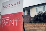 A red and white sign advertising a home for rent is erected in front of a small brick fence in front of a weatherboard house.