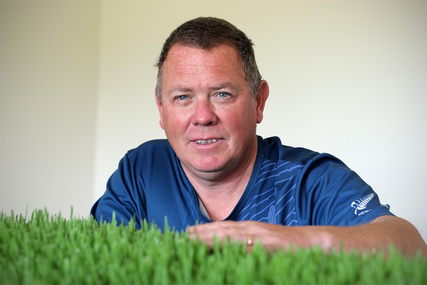 Alan Smith looks over some of his barley grass growing inside his shed.