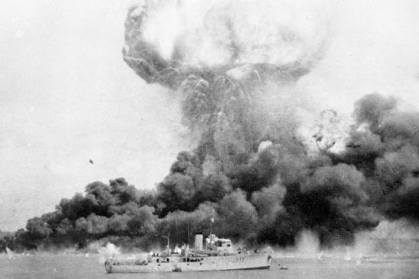 Dense clouds of smoke rise from oil tanks hit during the first Japanese air raid.