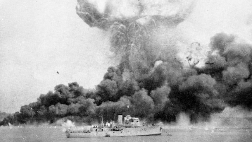 Dense clouds of smoke rise from oil tanks hit during the first Japanese air raid.