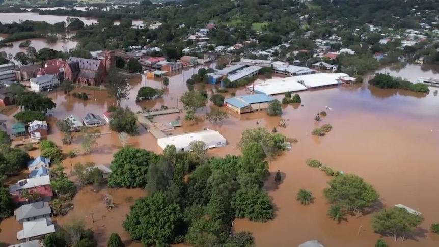 Aerial picture shows roofs of buildings above brown flood water.