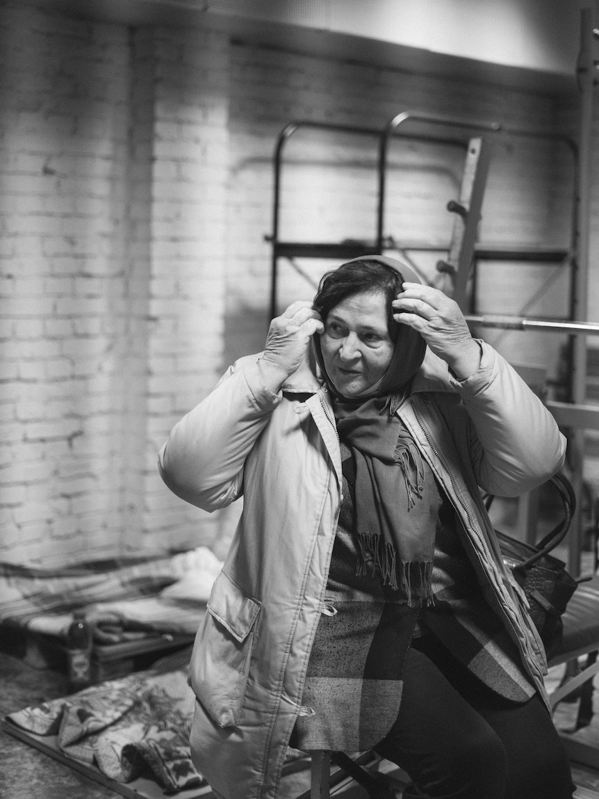 A black and white image of a Ukrainian woman fixing her hair in a bunker.