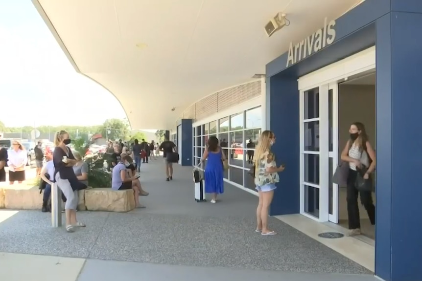 A building with an "Arrivals" sign and people walking around.