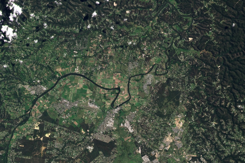 aerial view of a town and river its mostly green