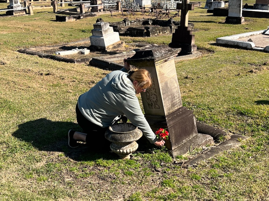 Tracey Oliviery puts flowers at the base of a grave.