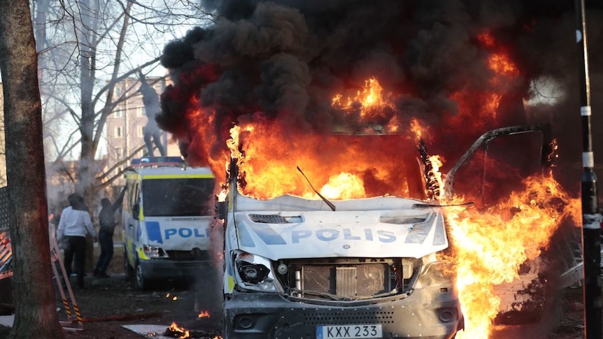 Swedish police vans are on fire during a counter-protest in a park
