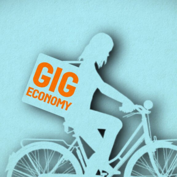 An image of a woman riding a bike with a pack on her back with the words in orange saying GIG ECONOMY