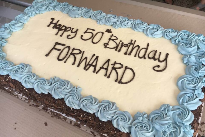 A cake with blue and white icing that says "Happy 50th Birthday FORWAARD".