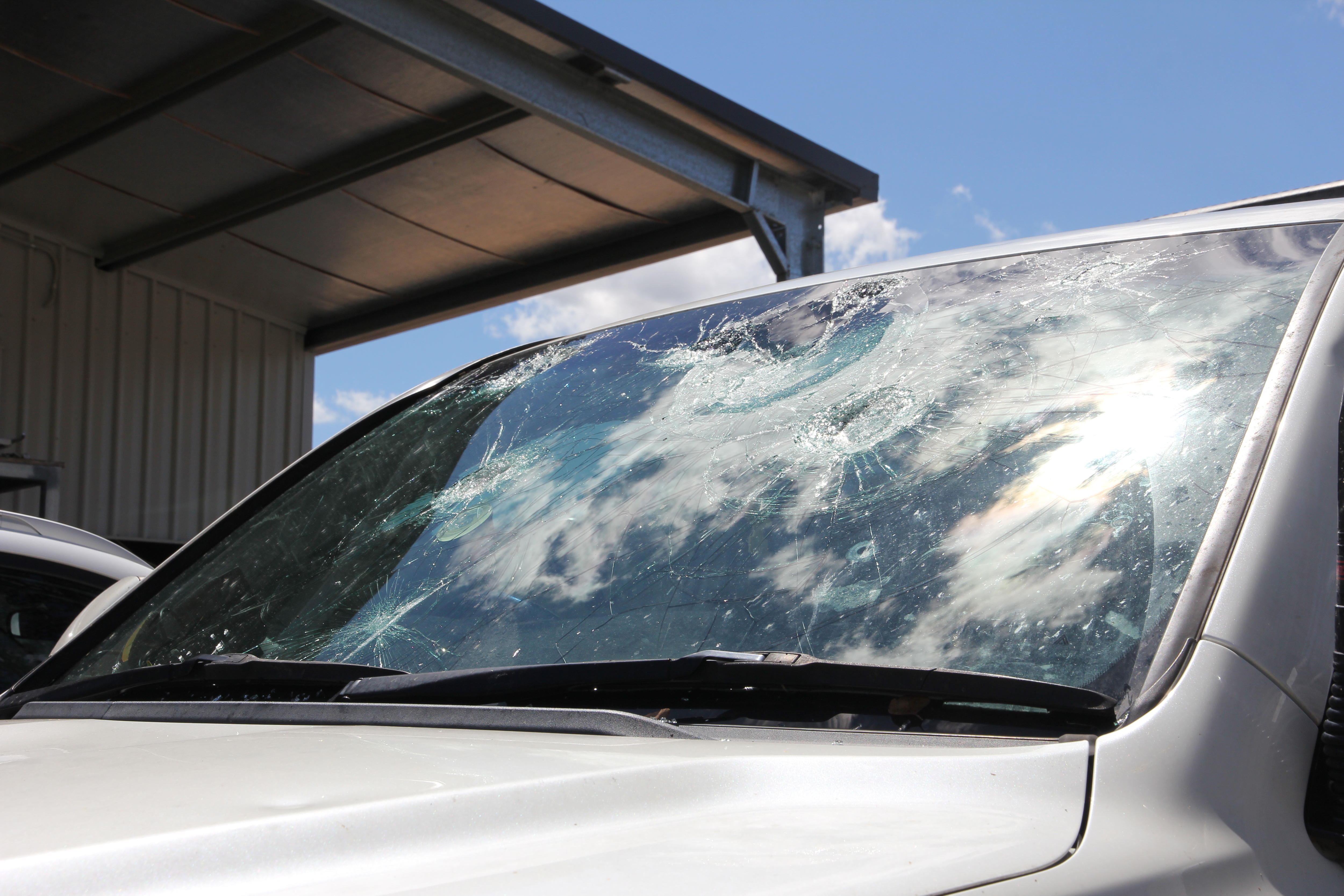 A car windscreen with several holes smashed in it.