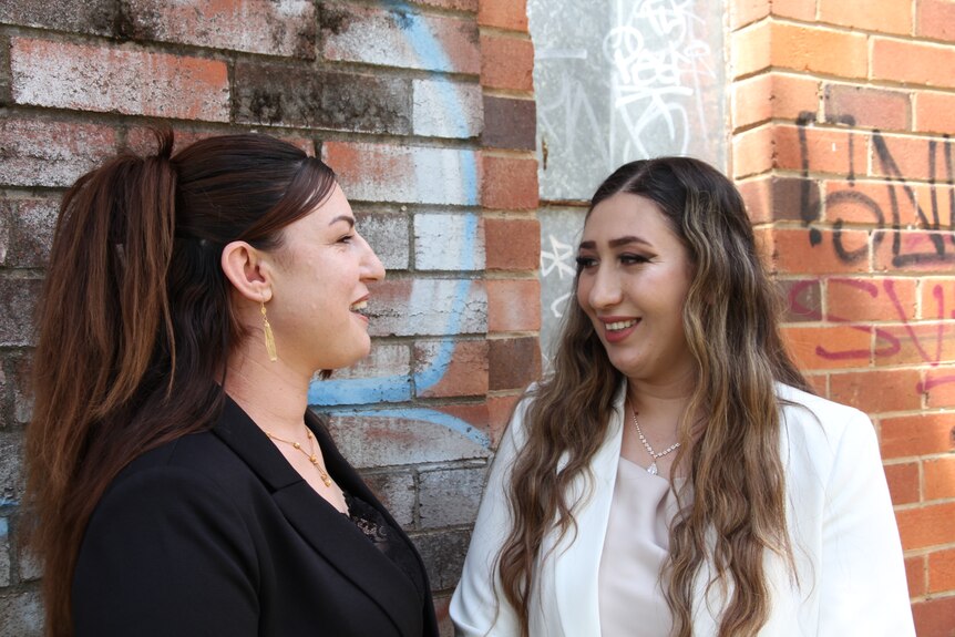 Two women, one in a black jacket, one in white, talking and laughing.