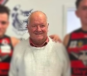 An older man with two football players beside him.
