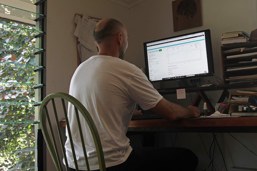 Michael Bruvel sits at a chair in front of his computer, with some temperature charts visible on the screen.