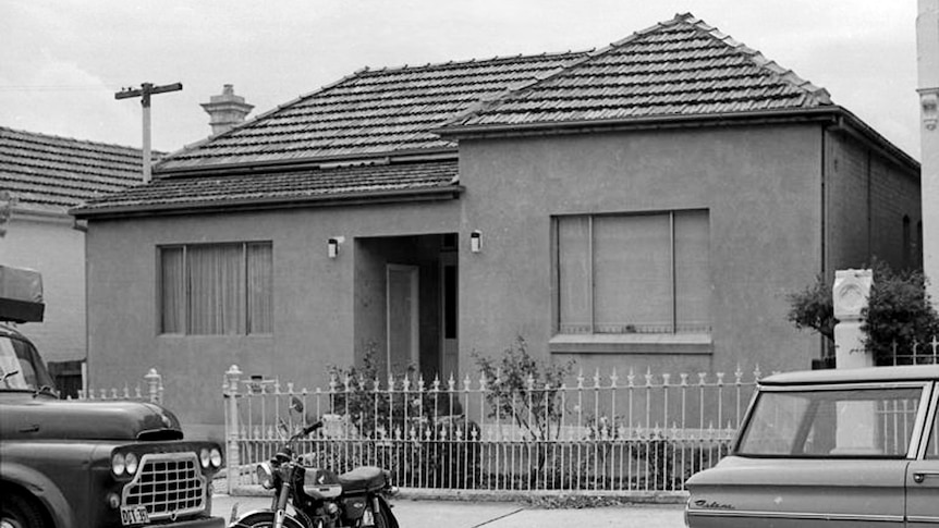 A black and white photo shows 1960s-era cars while a double-fronted home with a flat rendered facade.