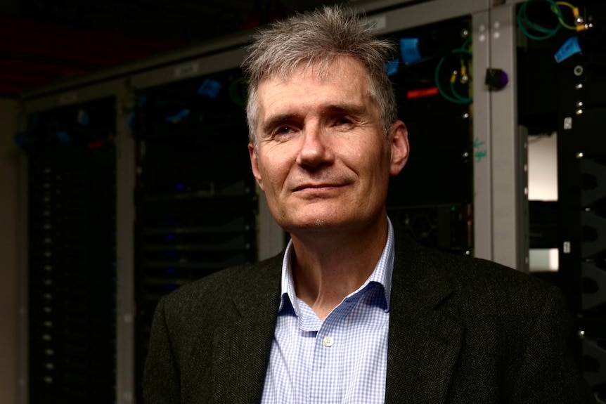 Richard Buckland stands in front of a computer panel.