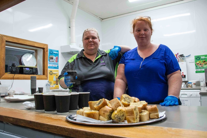 Two women serve food in a kitchen