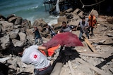 Rescue workers carry remains of a man from rubble next to a beachside cafe after it was hit by an sir strike in Gaza City