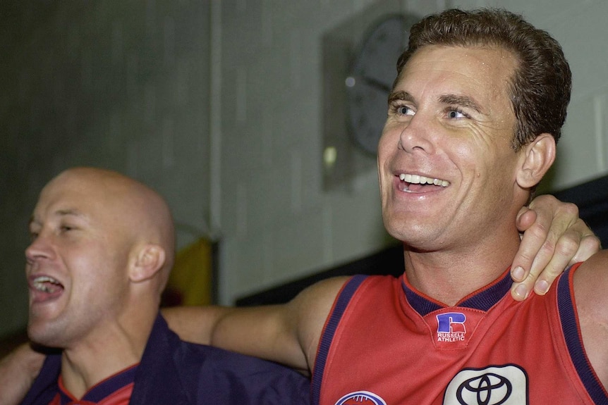 Wayne Carey and Nigel Smart sing with their arms around eatch others shoulders after the game