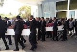 caskets and pallbearers at the funeral service for the two boys