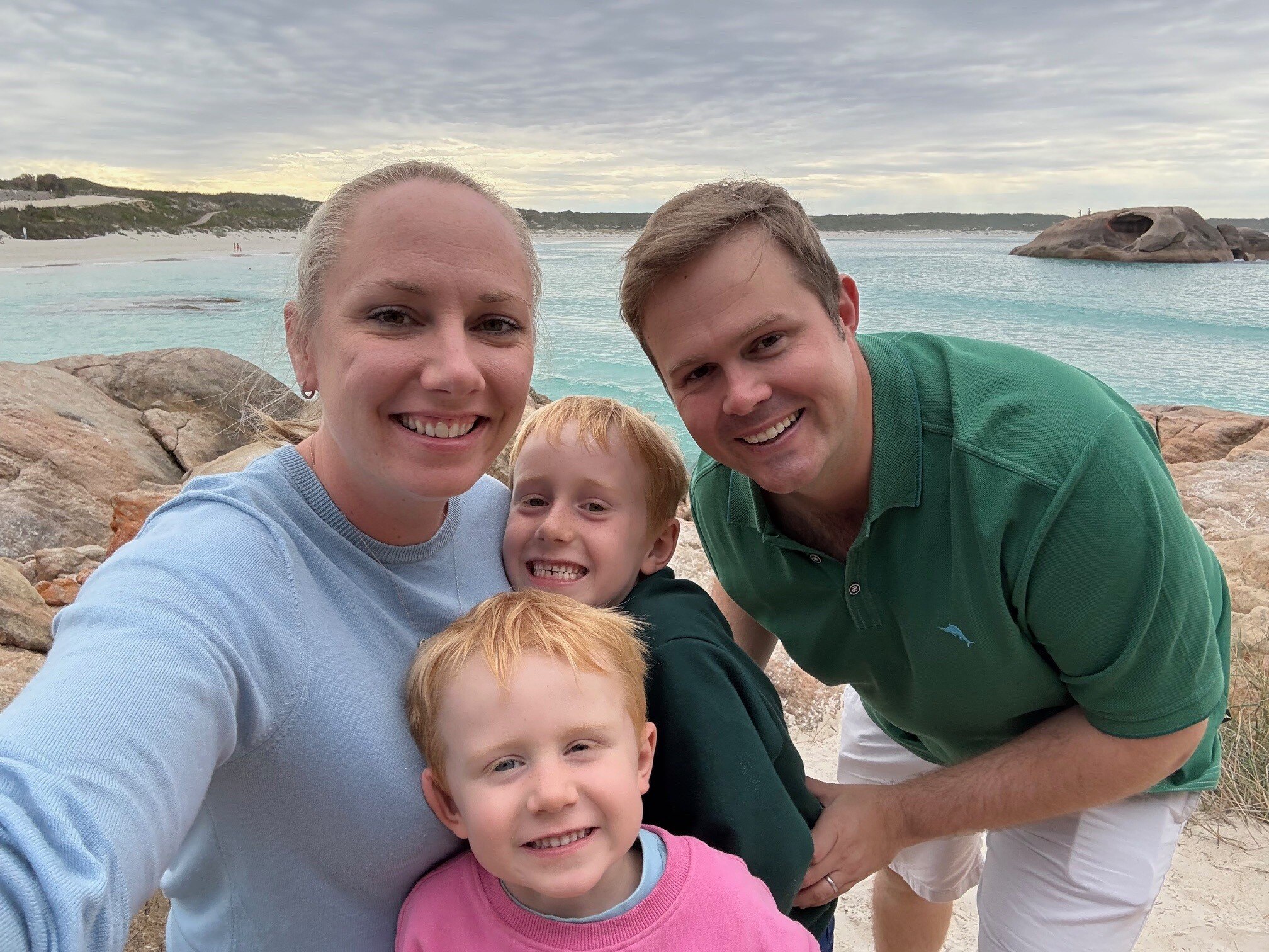 A man, woman and two children at the beach smile at the camera