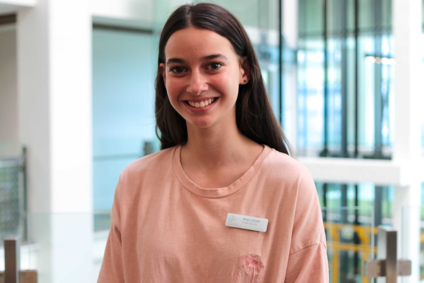 A teenage girl looks at the camera, smiling.