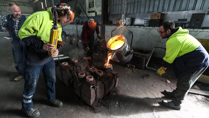 Max Billman (left) looks on as molten metal is poured into moulds.