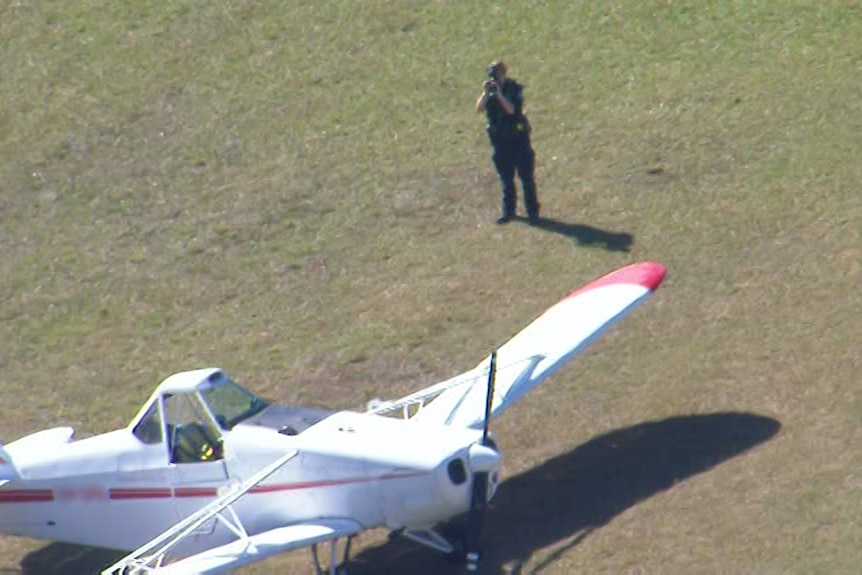 A police officer takes pictures of one of the planes involved in the collision at Caboolture Airfield.