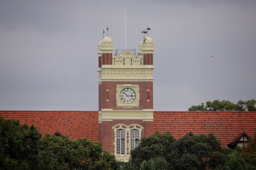 Torre del reloj en un edificio con tejas rojas en el techo. 