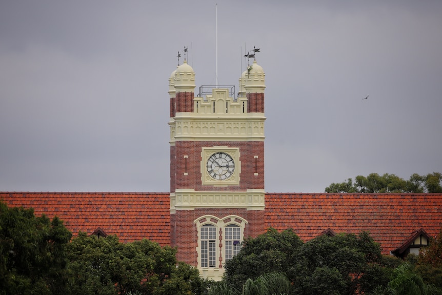 Clock tower on a building with red tiles on the roof. 