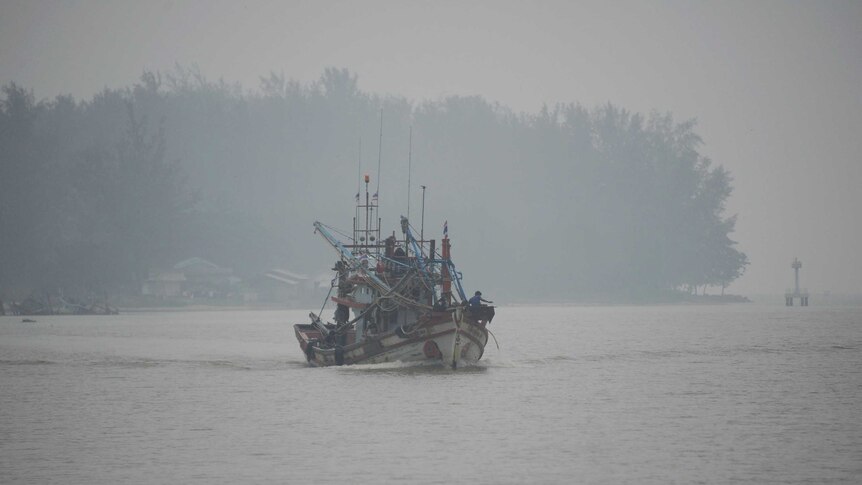 A fishing boat sails on the Narathiwat river through haze in southern Thailand