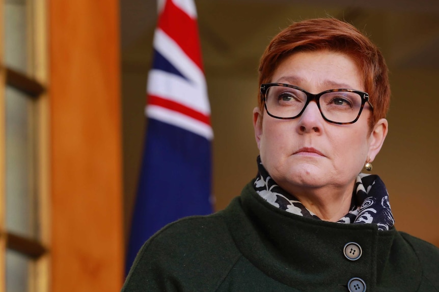 Marise Payne regarde au loin avec un drapeau australien derrière elle