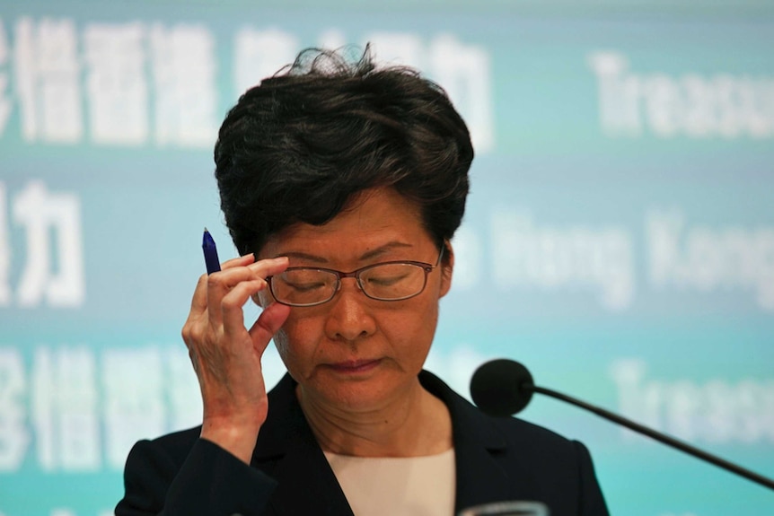 Hing Kong leader Carrie Lam looks downcast while giving a speech.