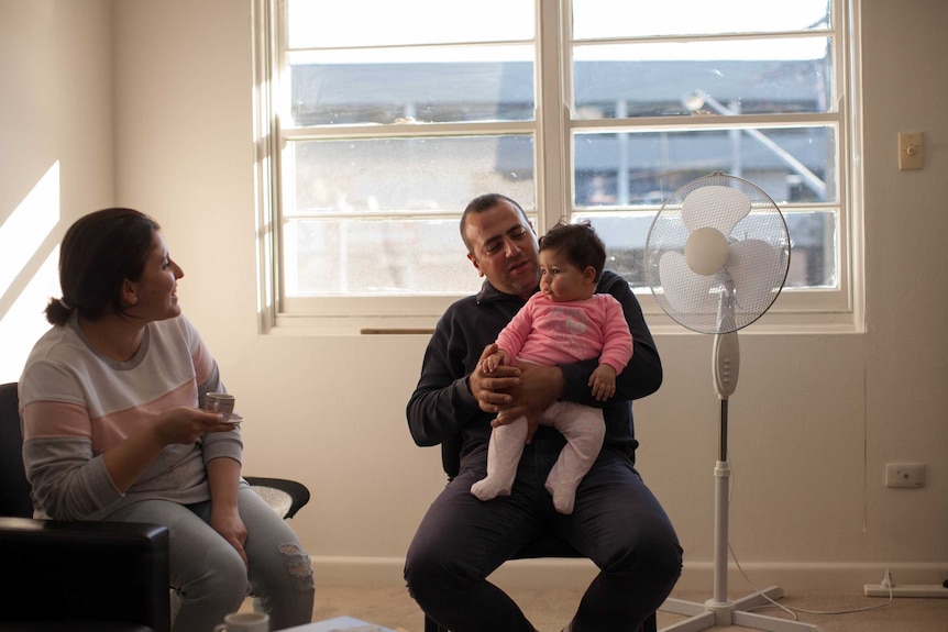 Mano holds his daughter Hasmig as she looks at her mother seated nearby