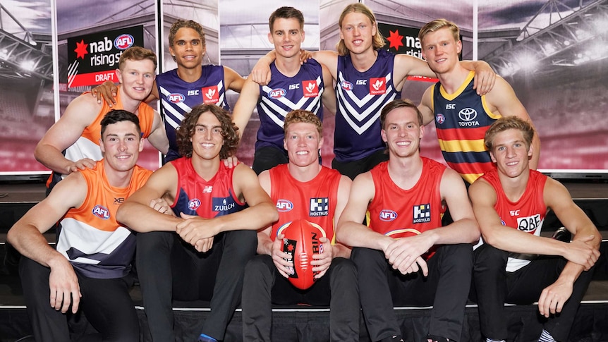 The top 10 AFL draft picks stand and sit as they pose for a photo.