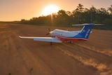 A Royal Flying Doctor Service plane takes off on a remote dirt airstrip. 