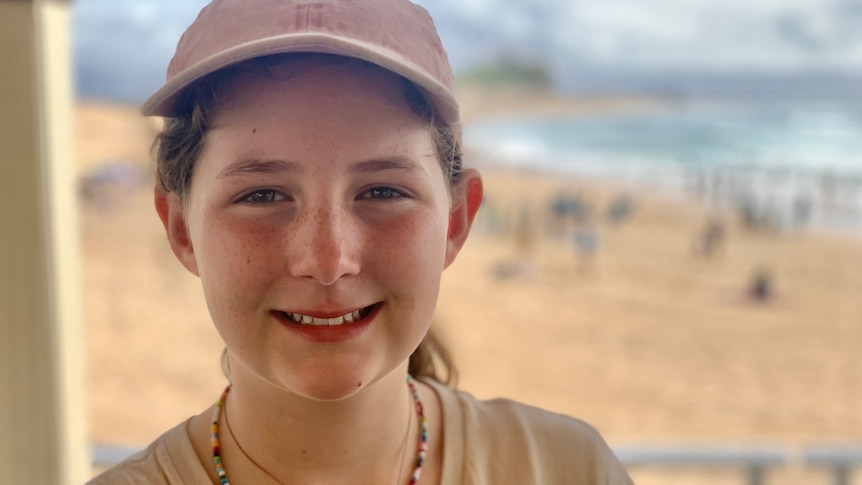 A young girl at the beach, smiling.