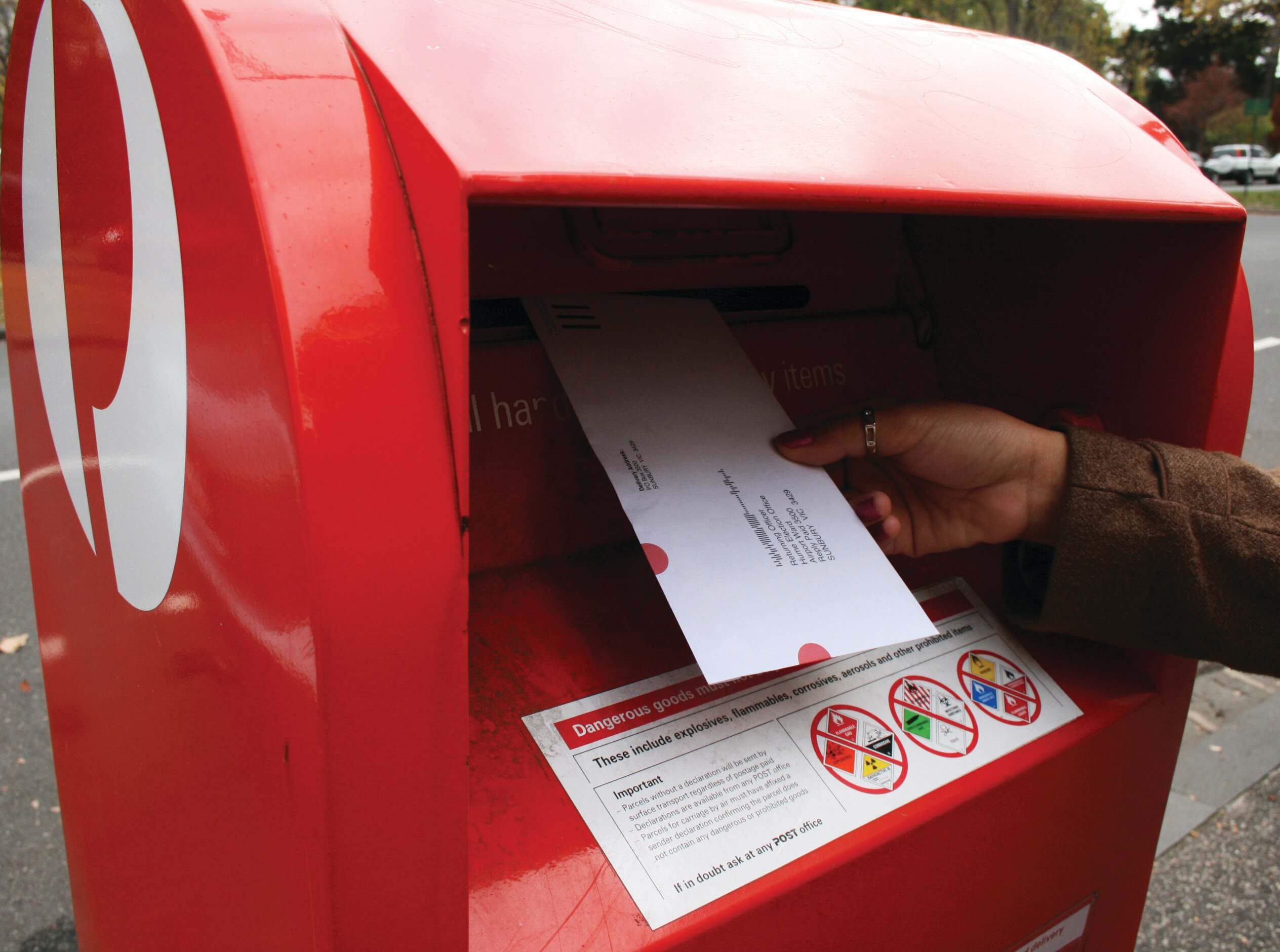 一个人试图把白色的信封投进一个红色的箱子里