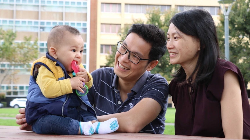 A man and woman smile as they look at their baby