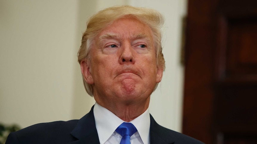 President Donald Trump listens intently while looking off to the side with his mouth closed.