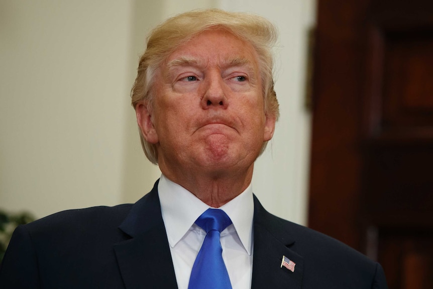 President Donald Trump listens intently while looking off to the side with his mouth closed.