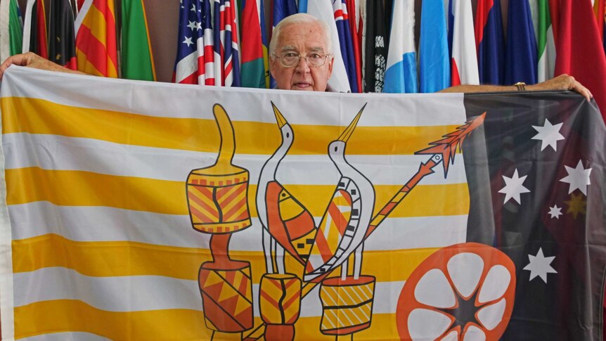 Flag store owner holding up very detailed copy of Tiwi island flag.