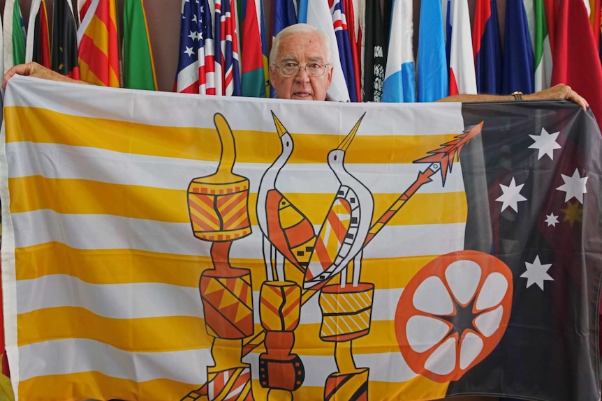 Flag store owner holding up very detailed copy of Tiwi island flag.